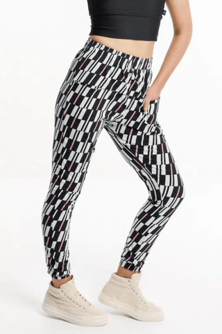 Woman wearing black and white patterned slim-fit leisure pants and cream sneakers.