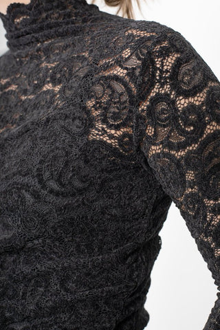 Close-up of a woman wearing a black floral lace high-neck top