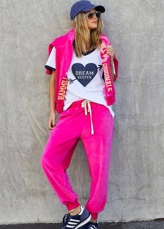 Woman wearing bright pink joggers, a white graphic t-shirt, and a matching pink sweatshirt.