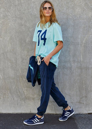 Woman wearing a light blue graphic t-shirt, navy blue joggers, and blue sneakers.