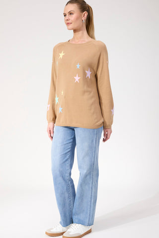Woman wearing a tan star-patterned sweatshirt and light blue wide-leg denim jeans.