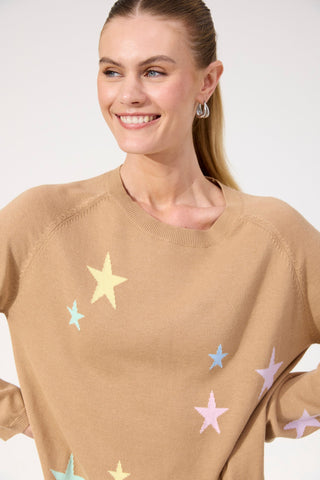 Smiling woman wearing a tan knit sweatshirt with pastel star patterns.