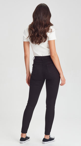 Woman wearing a white short-sleeve t-shirt and black slim-fit skinny pants with sneakers.