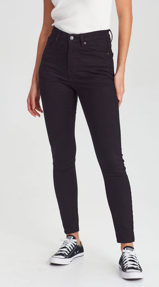 Woman wearing black slim fit skinny jeans and black and white canvas sneakers.