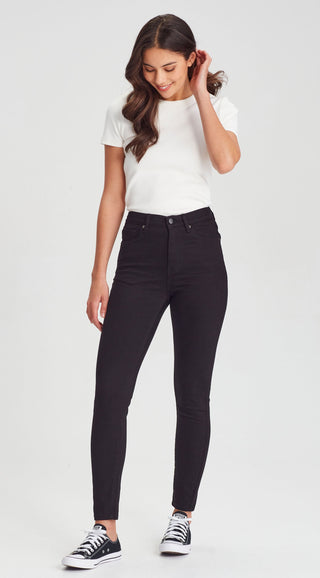 Woman wearing a white t-shirt and black high-waisted skinny jeans with black sneakers.