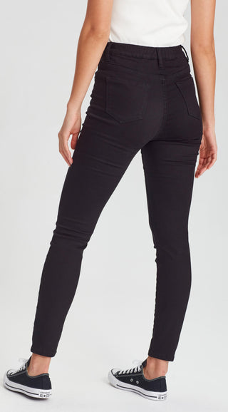 Woman wearing slim fit black skinny pants and black canvas sneakers.