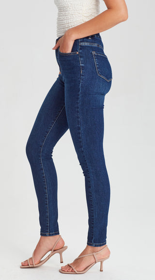 Woman wearing slim fit dark blue denim skinny jeans and beige heeled sandals.