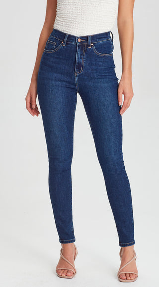 Woman wearing slim fit dark blue skinny denim jeans and nude strappy high heel sandals.