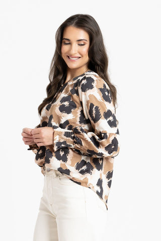 Woman wearing a brown and black leopard print blouse with white pants