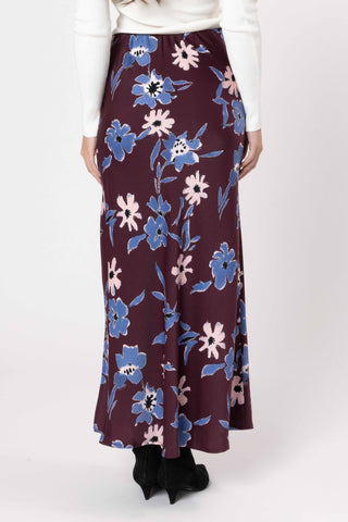 Woman wearing a long maroon floral maxi skirt with blue and pink flower patterns.