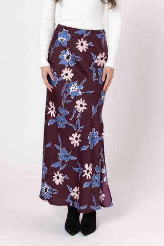 Woman wearing a long floral maxi skirt in plum with blue and pink flower patterns.