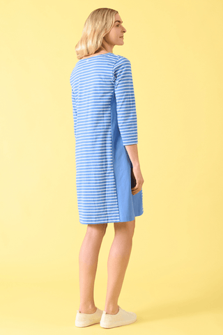 Woman wearing a blue and white striped three-quarter sleeve casual dress against a yellow background