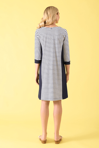 Woman wearing a navy and white striped three-quarter sleeve dress against a yellow background.