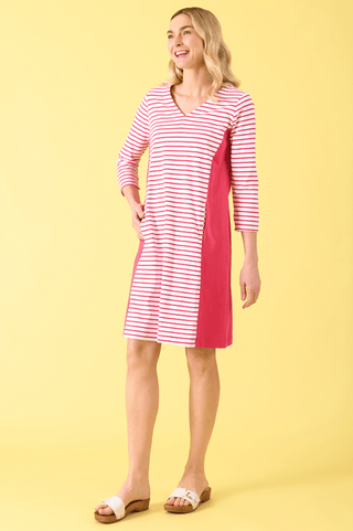 Woman wearing a red and white striped V-neck dress with color-block paneling and white sandals.
