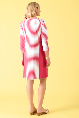 Woman wearing a pink and white striped three-quarter sleeve dress against a yellow background.