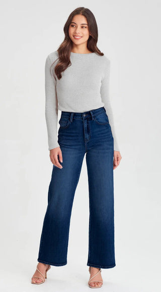 Woman wearing a grey long sleeve knit top and dark blue wide leg denim jeans.