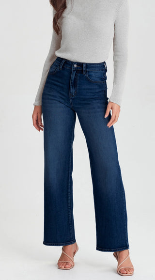 Woman wearing high-waisted dark wash wide leg denim jeans and a grey ribbed knit sweater.