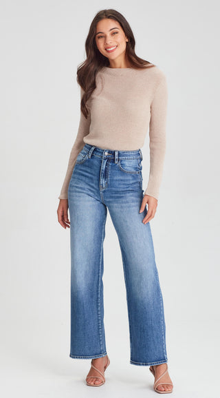 Woman wearing a beige ribbed long sleeve top and blue wide leg denim jeans