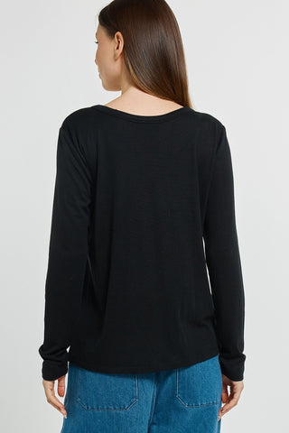 Back view of a woman wearing a plain black long-sleeved top and blue jeans.