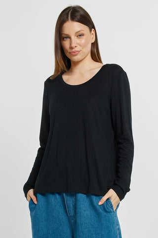Woman wearing a long-sleeved black top and blue denim pants