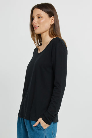 Woman wearing a black long sleeve t-shirt and blue denim jeans.