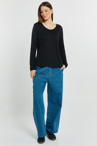 Woman wearing a black long sleeve top and wide leg blue jeans.
