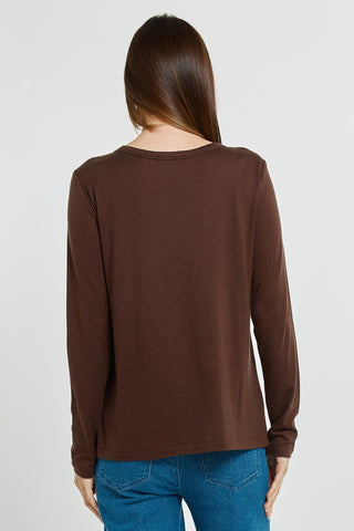 Rear view of a woman wearing a brown long sleeve top and blue jeans.