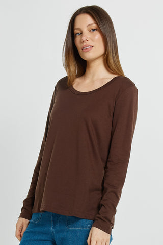 Woman wearing a brown long-sleeved scoop neck top and blue jeans.