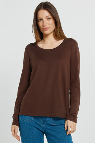 Woman wearing a brown long sleeve scoop neck top and blue jeans.