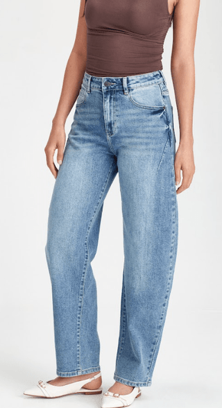 Woman wearing light wash blue straight leg denim jeans and white slingback flats.
