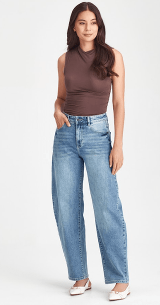 Woman wearing a brown sleeveless top and light blue wide-leg denim jeans.