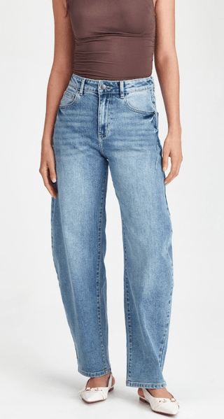 Woman wearing high-waisted light blue wide leg denim jeans and white ballet flats.