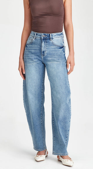 Woman wearing high-waisted light wash blue denim jeans and white ballet flats.