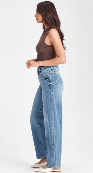 Woman wearing a brown sleeveless top and blue wide-leg denim jeans.