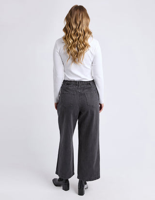 Woman wearing a white long-sleeve top and charcoal grey wide-leg pants from behind.