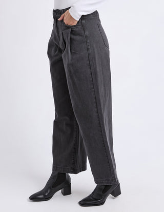 Woman wearing wide-leg charcoal grey denim pants and black heeled boots.