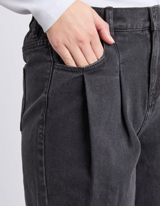 Close-up of a woman's hand in the pocket of charcoal grey denim pants